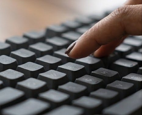 A finger pressing a key on a dark keyboard